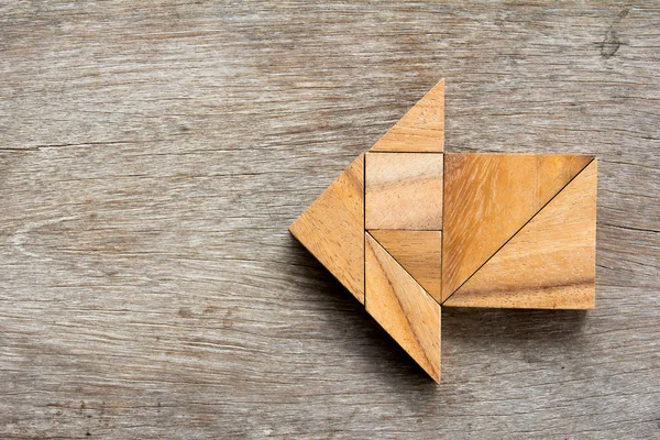Tangram bulmacanın ahşap arka plan üzerinde ok şeklinde