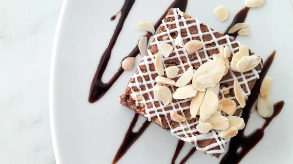 Felülnézete a háttér fehér lemez csokis brownie, szeletelt mandula — Stock Fotó