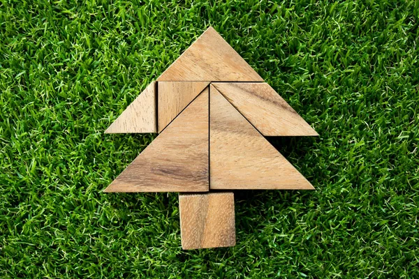 Rompecabezas de madera tangram en forma de árbol de Navidad sobre fondo de hierba verde artificial — Foto de Stock