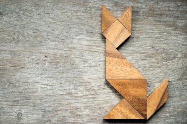 Tangram bulmacanın ahşap arka plan üzerinde kedi şeklinde