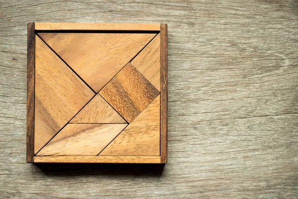 Rompecabezas Tangram en forma cuadrada con caja sobre fondo de madera —  Fotos de Stock