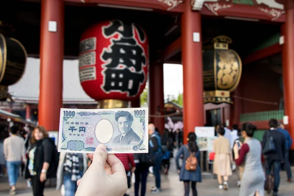 Tokyo, Japonya - 23 Nisan 2017: Bilgisiyle tutun 1000 Japonca yen banknot Asakusa tapınak arka kapıda Kaminarimon ile