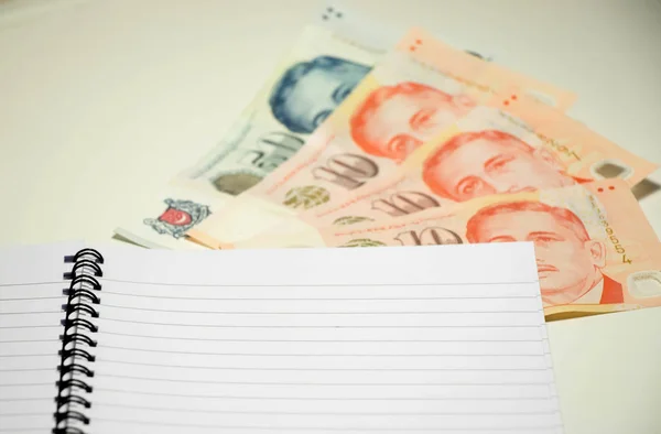 Książki pamiętać puste z Dolar singapurski na tle biały biurko — Zdjęcie stockowe