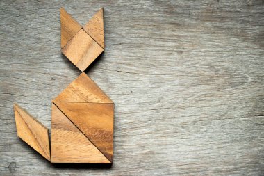Tangram bulmacanın ahşap arka plan üzerinde kedi şeklinde