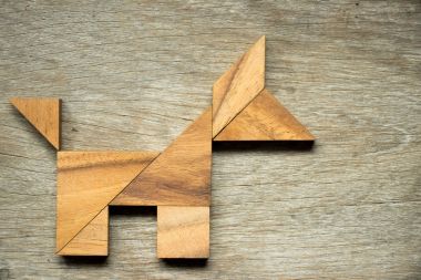 Tangram bulmacanın ahşap arka plan üzerinde köpek şeklinde