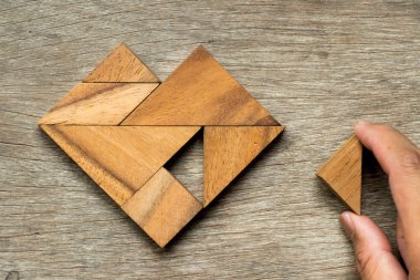 Tangram bulmacanın üçgen şeklinde ahşap zemin üzerine yerine getirmek için kalp şekli bekleyin