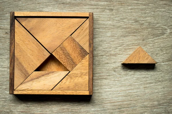 Tangram puzzle, négyzet alakú dobozban várni az beteljesülés egy háromszög darab fából készült háttér — Stock Fotó