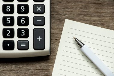 Ahşap arka plan üzerinde kalem ve hesap makinesi ile boş not defteri