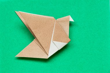 Kuş şekli yeşil arka plan üzerinde uçan kahverengi origami kağıt