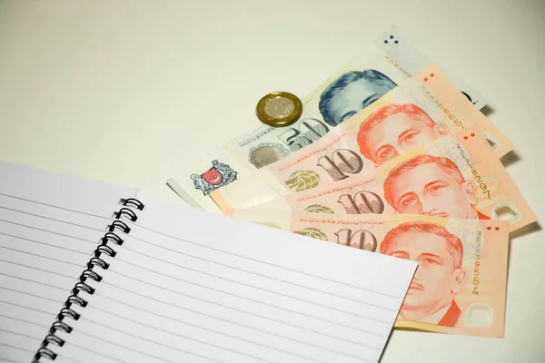 Książki pamiętać puste z Dolar singapurski na tle biały biurko — Zdjęcie stockowe