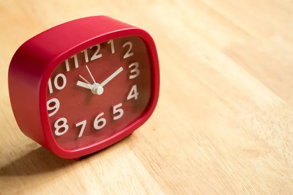 Reloj analógico rojo sobre fondo de mesa de madera — Foto de Stock