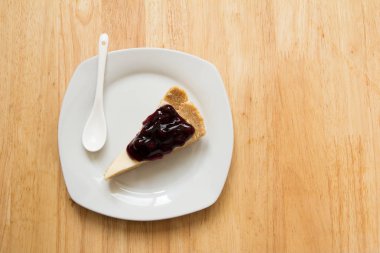 Yaban mersini peynir pastayla kaşık ahşap masa arka plan üzerinde beyaz çanak üzerinde