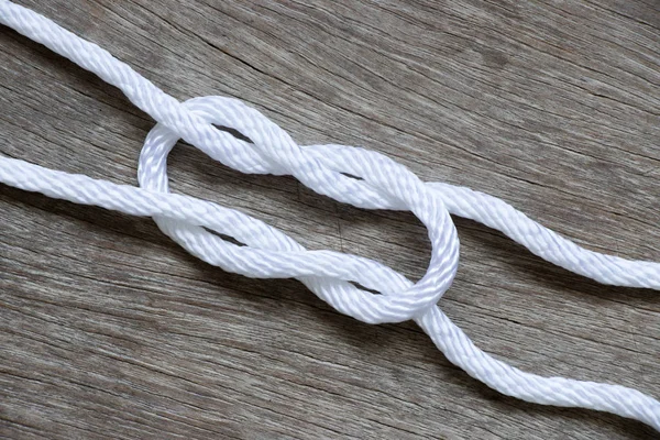 Biały sznur w węzeł prosty kształt na tle drewna — Zdjęcie stockowe