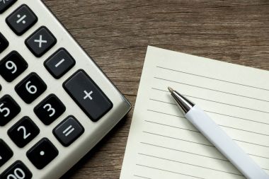 Ahşap arka plan üzerinde kalem ve hesap makinesi ile boş not defteri