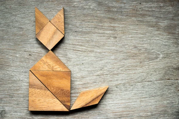 Tangram bulmacanın ahşap arka plan üzerinde kedi şeklinde
