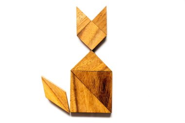Ahşap tangram bulmacanın içinde şekil beyaz arka plan üzerinde oturan kedi