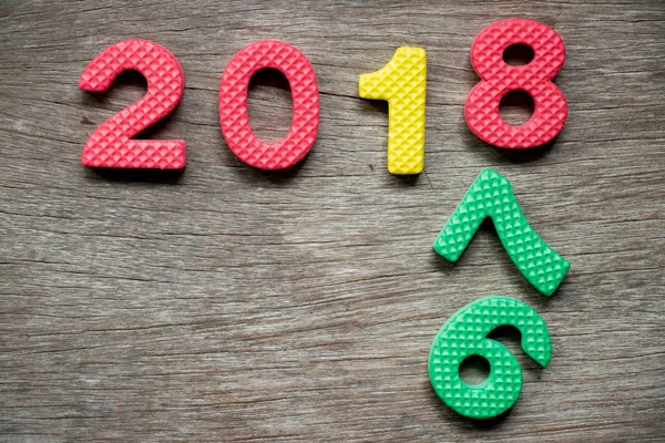 Toy foam alphabet in wording 2018 and falling number 6 and 7 on wood background (Concept for Happy new year) — Stock Photo, Image