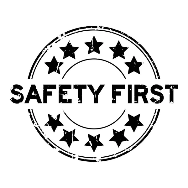 Grunge black safety first wording with star icon round rubber seal stamp on white background — Stock Vector