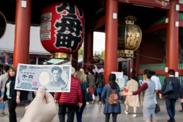 Tokyo, Japonya - 23 Nisan 2017: Turist tutun 1000 Japonca yen banknot Asakusa tapınak arka kapıda Kaminarimon ile