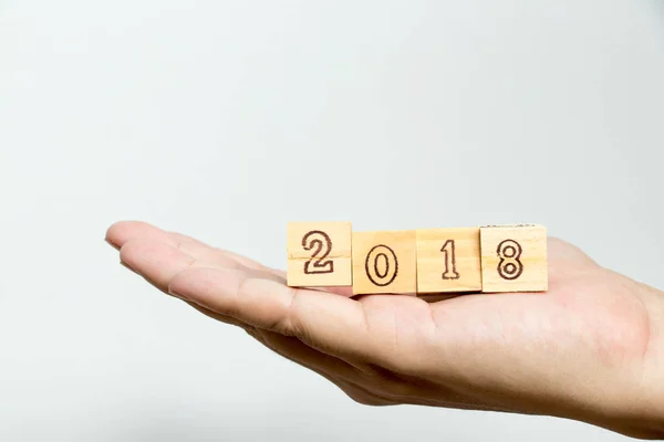 Man hold bloco de madeira com redação 2018 em fundo de concreto (Conceito para o feliz ano novo 2018 ) — Fotografia de Stock