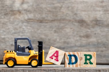 Sarı Plastik forklift tutun kelime Adr (kısaltma olumsuz uyuşturucu reaksiyon) ahşap arka plan üzerinde tamamlamak için A harfi