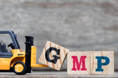Sarı Plastik forklift tutun kelime Gmp (kısaltma, iyi Manufacturinc Practice) ahşap arka plan üzerinde tamamlamak için G harfi