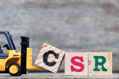 Sarı Plastik forklift tutun kelime Csr (kurumsal sosyal sorumluluk kısaltma) ahşap arka plan üzerinde tamamlamak için C harfi 