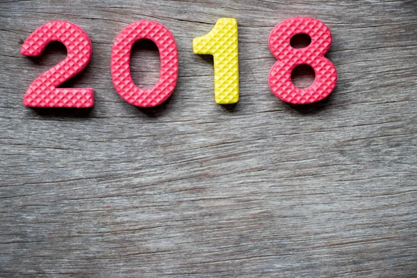 Alfabeto in schiuma giocattolo nella formulazione 2018 su fondo piatto di legno (concetto per felice anno nuovo decorazione ) — Foto Stock