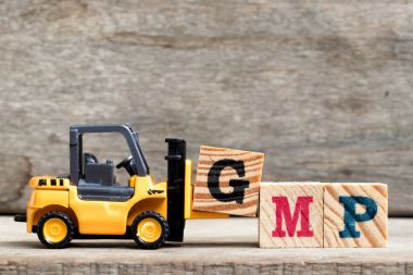 Sarı Plastik forklift tutun kelime Gmp (kısaltma iyi üretim uygulaması) ahşap arka plan üzerinde tamamlamak için G harfi
