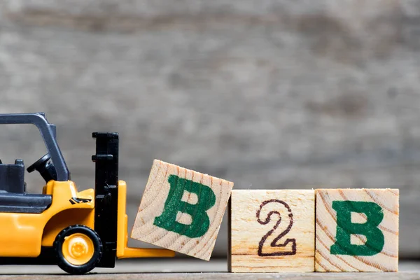 Sarı Plastik forklift mektup B tam word B2b (Business iş için) ahşap arka plan üzerinde tutun
