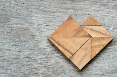 Ahşap arka plan üzerinde kalp şeklinde bulmaca Tangram