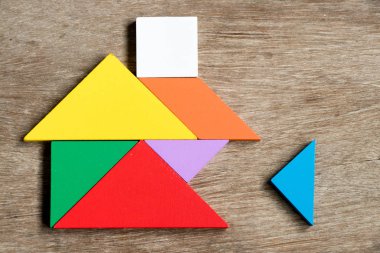 Renkli tangram bulmacanın ev şekli bekleyin için yerine getirmek ahşap arka plan (konsept yapı rüya evi, mutlu aile hayatı, gayrimenkul yatırım üzerinde)