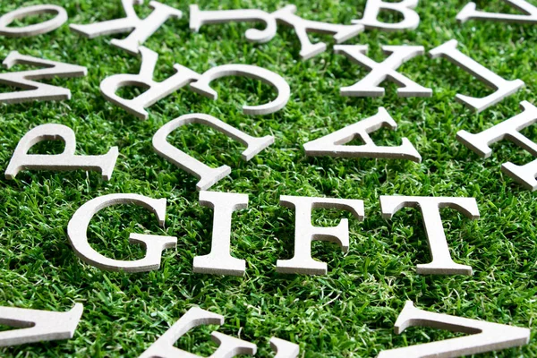 Alfabeto de madera en regalo de redacción sobre fondo de hierba verde artificial —  Fotos de Stock