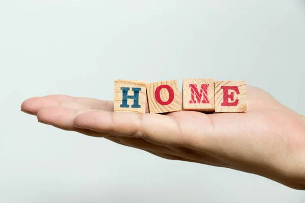 Man hold wood block with wording home on concrete background — Stock Photo, Image