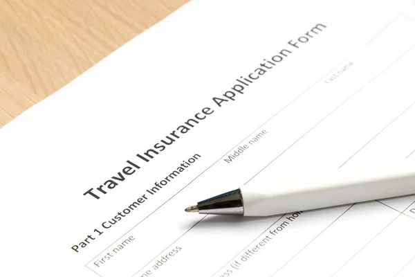 Заявка на страхування подорожей чекає, щоб заповнити інформацію на фоні столу — стокове фото