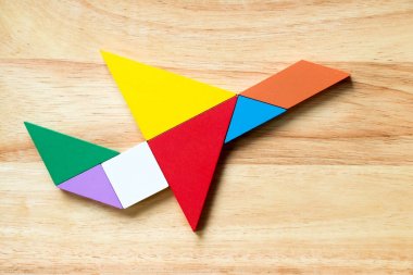 Uçak şekil ahşap arka plan üzerinde uçan renk tangram bulmacanın