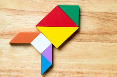 Renk tangram bulmacanın ahşap arka plan üzerinde roket veya füze şeklinde