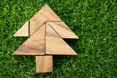 Ahşap tangram bulmacanın suni yeşil çim zemin üzerine Noel ağacı şeklinde