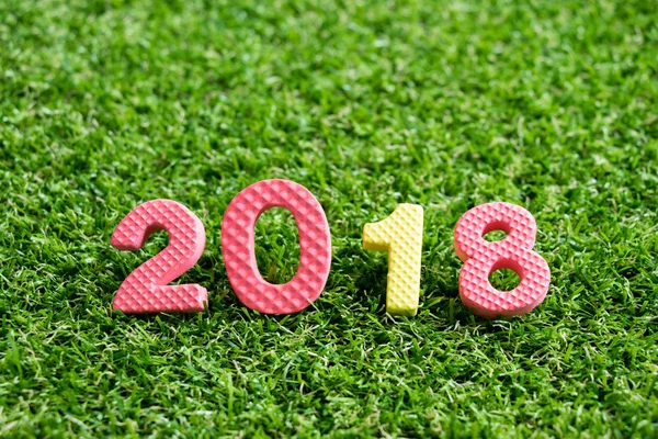 Oyuncak köpük alfabe arka planda ifade 2018 üzerinde yapay yeşil çim (Happy new year dekorasyon konsepti) — Stok fotoğraf