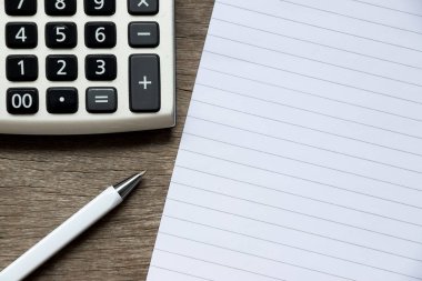 Ahşap arka plan üzerinde kalem ve hesap makinesi ile boş not defteri