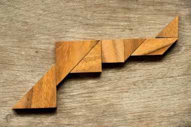 Ahşap tangram bulmacanın silah şekli arka planda
