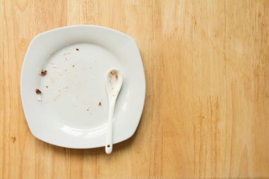 Kirli beyaz plaka ve tatlı gıda hurda ahşap zemin üzerine kaşıkla