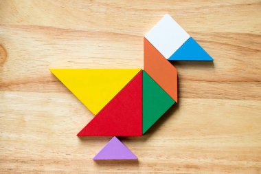 Renk tangram bulmacanın ahşap arka plan üzerinde kuş şeklinde