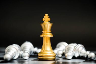 Satranç oyununda altın kral siyah zemin üzerinde başka bir gümüş takım ile karşı karşıya (Şirket stratejisi, iş zaferi veya karar kavramı)