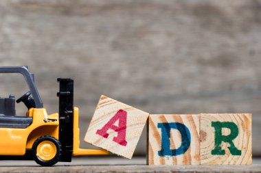 Sarı Plastik forklift tutun kelime Adr (kısaltma olumsuz uyuşturucu reaksiyon) ahşap arka plan üzerinde tamamlamak için A harfi