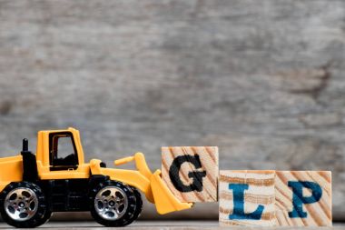 Sarı Plastik Paletler-Düzleme paleti tutun kelime Glp (iyi laboratuar Practicee kısaltması) ahşap arka plan üzerinde tamamlamak için G harfi