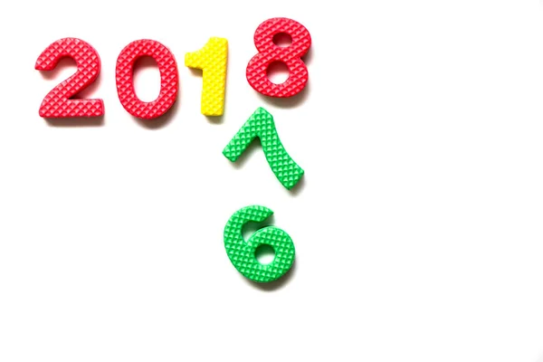 Spielzeugschaumstoff-Alphabet im Wortlaut 2018 und fallende Zahlen 6 und 7 auf weißem Hintergrund (Konzept für ein glückliches neues Jahr)) — Stockfoto