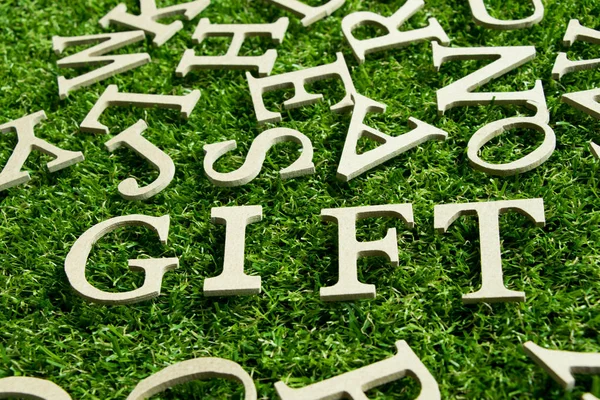 Alphabet en bois dans la formulation cadeau sur fond de gazon vert artificiel — Photo