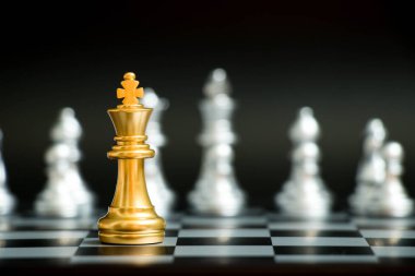Satranç oyununda altın kral siyah zemin üzerinde başka bir gümüş takım ile karşı karşıya (Şirket stratejisi, iş zaferi veya karar kavramı)