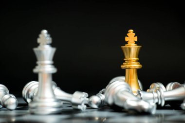 Satranç oyununda altın kral siyah zemin üzerinde başka bir gümüş takım ile karşı karşıya (Şirket stratejisi, iş zaferi veya karar kavramı)